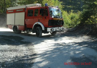 Ein Feuerwehr LKW fährt einen Seinbruch Runter auf einer Kiesstraße um die Kurve rum, im Hintergrund ein paar Bäume die den Hang hinauf gehen beim Schadenpräventionstraining