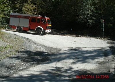 Ein Feuerwehr LKW fährt einen Seinbruch Runter auf einer Kiesstraße um die Kurve rum, im Hintergrund ein paar Bäume die den Hang hinauf gehen beim Schadenpräventionstraining