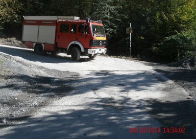 Ein Feuerwehr LKW fährt einen Seinbruch Runter auf einer Kiesstraße um die Kurve rum, im Hintergrund ein paar Bäume die den Hang hinauf gehen beim Schadenpräventionstraining