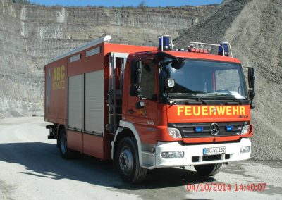 Ein Feuerwehr LKW steht in einen Steinbruch , im Hintergrund hohe Steinwände die hinauf gehen beim Schadenpräventionstraining