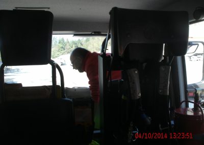 Hinterer Innenraum des Feuerwehr Farzeuges, vorne auf dem Beifahrersitz sitzt ein Mitarbeiter und schaut richtung Fahrersitz