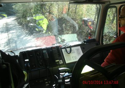 Hinterer Innenraum des Feuerwehr Farzeuges, vorne auf dem Beifahrersitz sitzt ein Mitarbeiter und schaut richtung Fahrersitz und links sieht man angedeutet den Fahrer