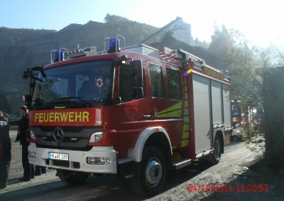 Nahaufnahme eines Feuerwehr einsatz fahrzeuges, im Hintergrund hohe Steinwand und hinter dem Wagen steht noch ein Fahrzeug